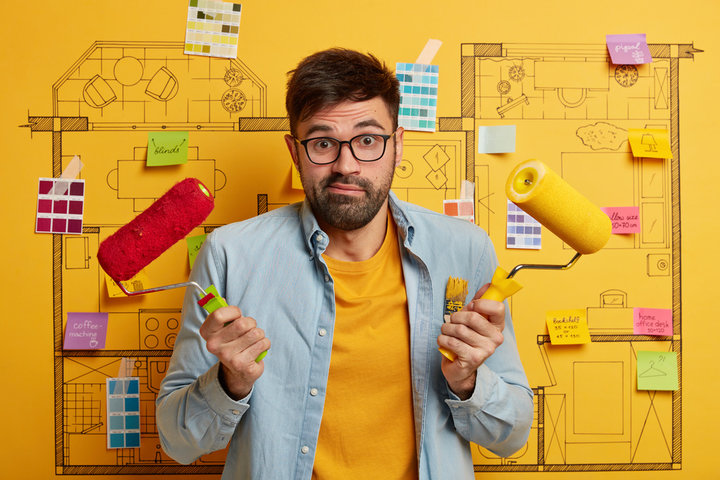 um homem com dois rolos de pintar parede na mão