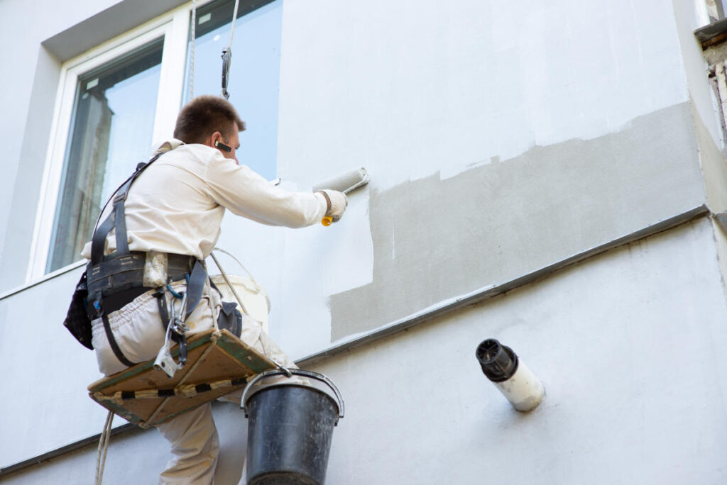 um homem pintando a fachada de um prédia é um funcionário da halluart